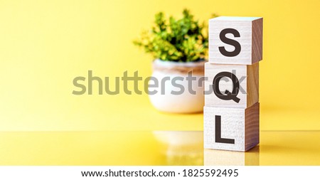SQL - Structured Query Language - concept, cube wooden block with alphabet combine abbreviation SQL. Bright Yellow background.