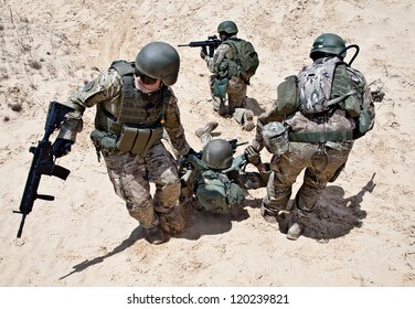 Squad of soldiers evacuate the injured fellow in arms in the desert