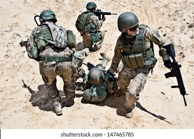 Squad of soldiers evacuate the injured fellow in arms in the desert