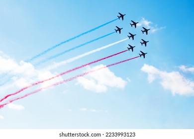 Squadron of planes fly with color trail in blue red white lines over clouds and clear sky in colors of USA Holland or France
