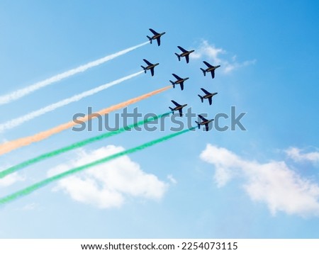 Squadron of planes fly with color trail lines of India or Cote d'Ivoire over clouds and clear sky