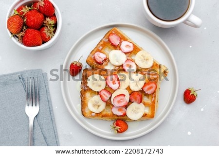 Square belgian waffles with strawberries berries,bananas,condensed milk,honey on plate, cup of coffee espresso. Tasty breakfast, sweet dessert food.selective focus, close up top view flat lay.