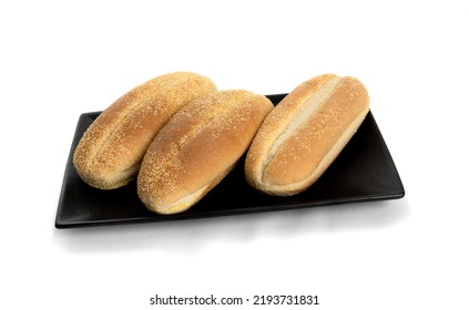 A Square Black Plate Of Three Seed Hotdog Buns Isolated On White