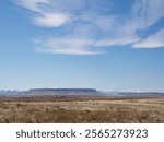 Square Butte mountain in the distance with a valley with dried grass in the foreground. Photographed in Montana.