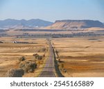 Square Butte, near Fort Shaw, Montana, photographed in morning light. A valley with grazing cattle, silos, and a highway are in the foreground.