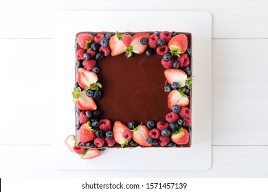 Square cake on birthday decorated with fresh berries, poured with chocolate on a white background. Top view - Powered by Shutterstock