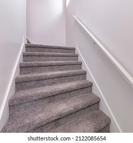 Square Carpeted stairs with wall-mounted white handrailing upstairs - Shutterstock ID 2122085654