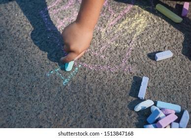 Square Chalk Of Different Sizes For Drawing. The Hand Of A Drawing Child. Child Draws Patterns On Asphalt