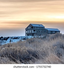 Square Crop Solitary Home On Snowy Hill With Flowering Wild Grasses In The Foreground