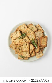 Square diet cookies with rosemary, flax seeds and spices  in a light plate on white background. Crunchy herbal crackers top view