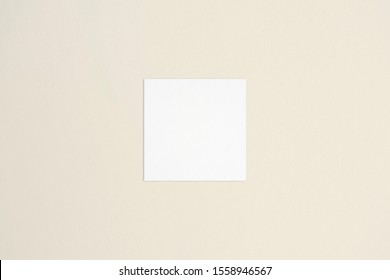 Square Empty White Business Card Mockup On Bone Coloured Background. Flat Lay, Top View. For Branding Identity, Logo Design Pitches And Marketing.