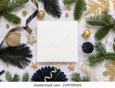 Square Envelope Between Black And Golden Christmas Decorations And Fir Tree Branches Top View. Winter Composition With Blank Invitation Card Mockup, Copy Space