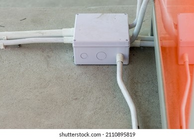 Square Flooring box with plastic pipes and electric cables. White electrical junction box and wires on the floor.  Installation of electrical wiring on the concrete floor. 