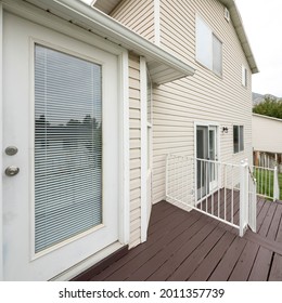 Square Frame Exterior Of A House With Vinyl Wood Wall, Elevated Wooden Deck And Doors With Glass Panels