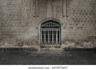 square frame window with a forged metal grill against a wall of beige stone blocks. one arched window behind iron bars on rock wall. sidewalk outside. paving cobbled floor. Dadiani Palace - Powered by Shutterstock