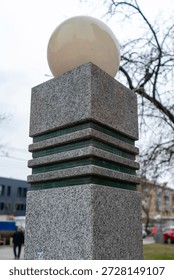 A square granite column with a spherical lantern on top. A city lantern.