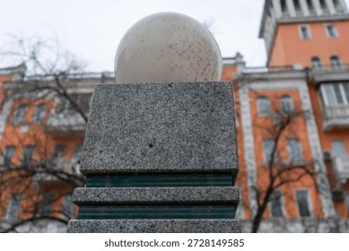 A square granite column with a spherical lantern on top. A city lantern.