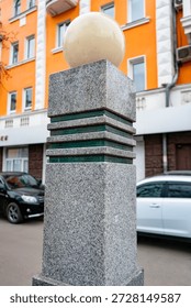 A square granite column with a spherical lantern on top. A city lantern.