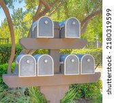 Square Mailboxes rack at Ladera Ranch in Southern California. Mailboxes near the plants and trees outside the fenced residences at the back with handrails on the left.