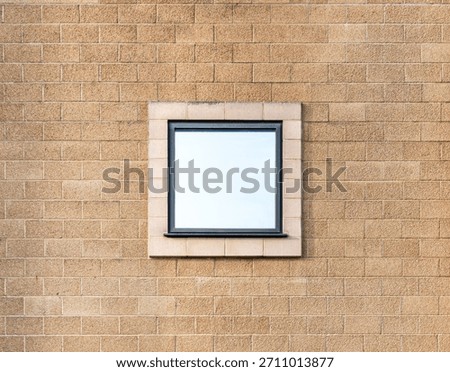 square mirror reflective window centred on an orange brick wall