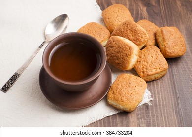 Square mug of tea with shortbread biscuits, on a brown table and a napkin