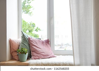 Square pillows, plaid and plant at the window. Reading corner 