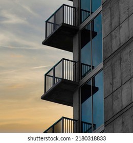 Square Puffy clouds at sunset Side of a tall building with railings on the balconies at Salt Lake City, Utah. Exterior of a building with wall and glass on the right against the dark cloudy sky