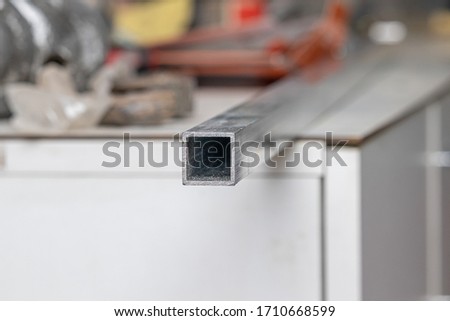 A square section of aluminum pipe lies on a table in a locksmith's shop