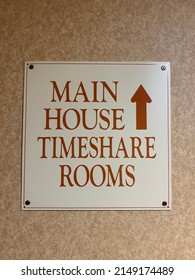 A square sign that reads "MAIN HOUSE TIMESHARE ROOMS" with an arrow pointing in the direction of the labeled hotel accommodations.