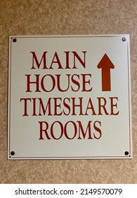A square sign that reads "MAIN HOUSE TIMESHARE ROOMS" with an arrow pointing in the direction of the labeled hotel accommodations.
