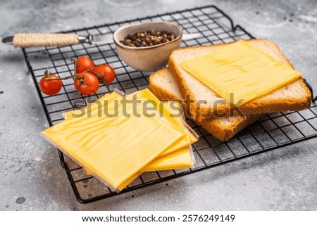 Square Slices of processed Cheddar cheese in individual plastic packaging. grey background. top view.