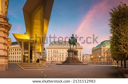 Square with statue in front an museum building Albertina in Vienna and historical hotel Sacher and Vienna state opera in the background during evening