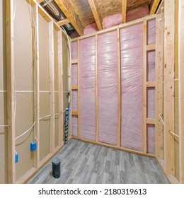 Square Unfinished Bathroom Construction With Woodframes And Wooden Flooring. There Is A Wall Insulation At The Front Wall And A Plywood On The Sides And Pipes On The Floor.