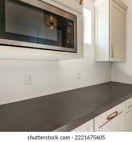 Square White Kitchen Interior With Alcove Sleek Dark Gray Kitchen Countertop. There Is A Microwave Oven Below The Wall Cabinet On The Left Near The Window Beside The Cabinet On The Right.