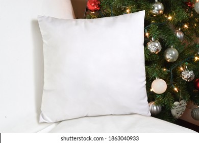 Square White Throw Pillow Napping Lazily On A White Couch. A Festive Lit Up Christmas Tree Adds Holiday Flair To This Pillow Mockup.