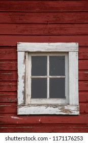 Square window with a white frame on an old red barn.