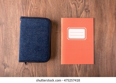 Squared exercise book and pencil case on the wooden background