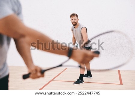 Squash, man and racket serve at gym, competition and team for indoor fitness or tournament. Male person, friends and court for physical training or workout, practice gear and athletes for exercise