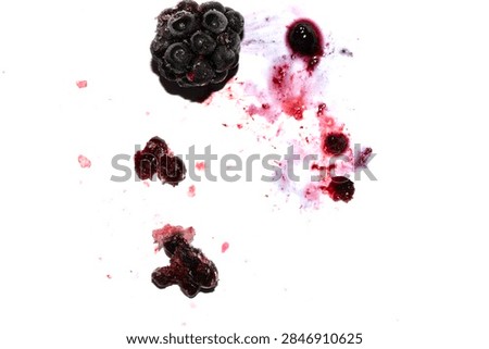 Squashed exploding and crushed blackberries fruit berries splattered on a white background with juice