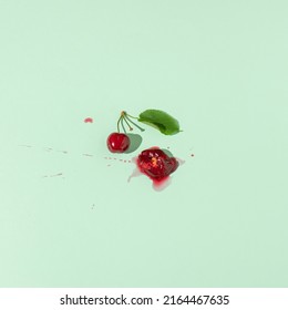 Squashed red cherry berry fruit on pastel green background. Summe red ripe juicy fruit concept.