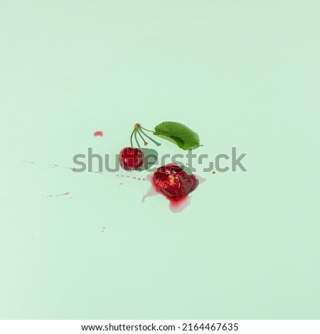 Squashed red cherry berry fruit on pastel green background. Summe red ripe juicy fruit concept.