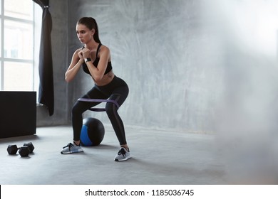 Squats. Sports Woman In Fashion Clothes Squatting With Band