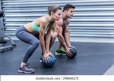 Squatting muscular couple doing ball exercise - Powered by Shutterstock