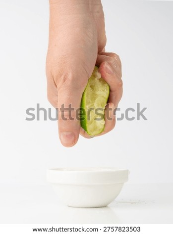 Squeezed lime isolated, hand squeezing out half green lemon, squeezed lime juice on white background, burnout symbol, making a Cuba Libre cocktail