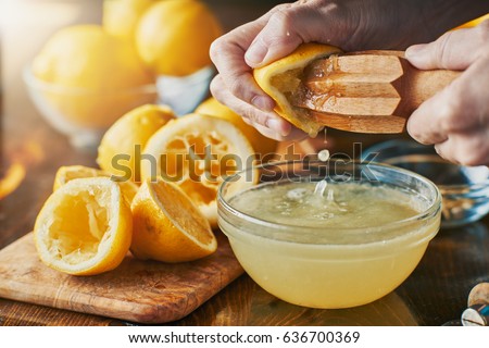 squeezing fresh lemon juice with wooden reamer into bowl