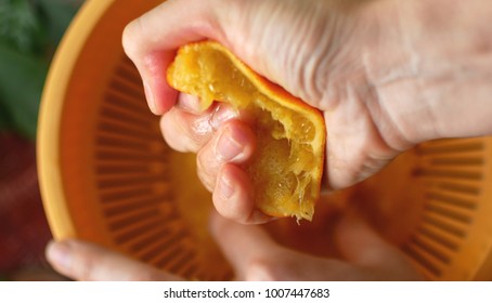 Squeezing orange juice by hands on juicemachine