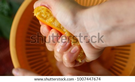 Squeezing orange juice by hands on juicemachine
