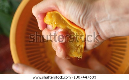 Squeezing orange juice by hands on juicemachine