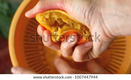 Squeezing orange juice by hands on juicemachine