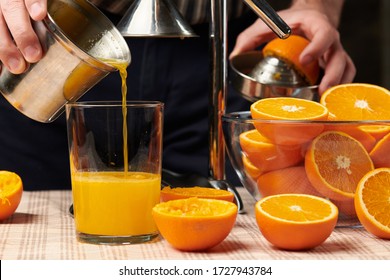 Squeezing an orange with a manual press, close view, making a glass of fresh. Fresh oranges on a wooden table, whole, squeezed and sliced. - Powered by Shutterstock